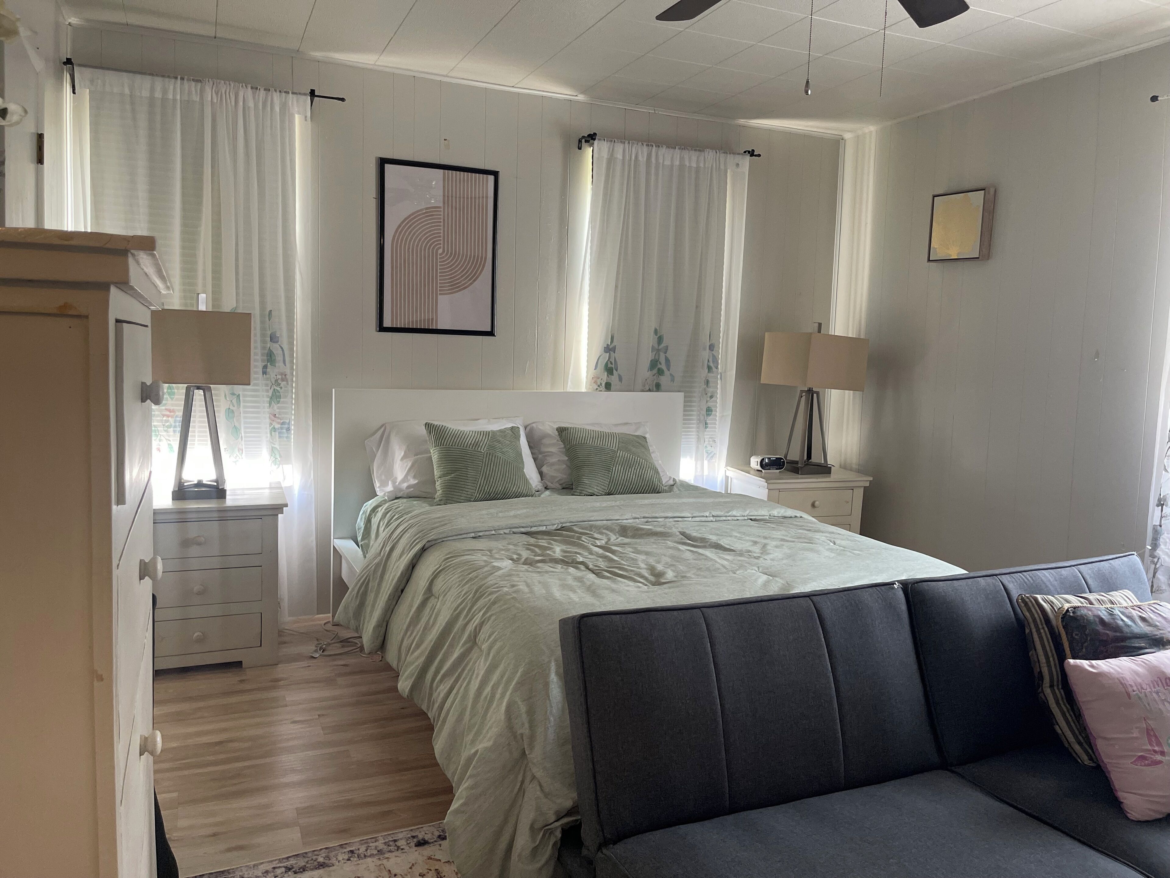 A bedroom with a bed, bedside tables, a dresser, a lamp, and a sofa.