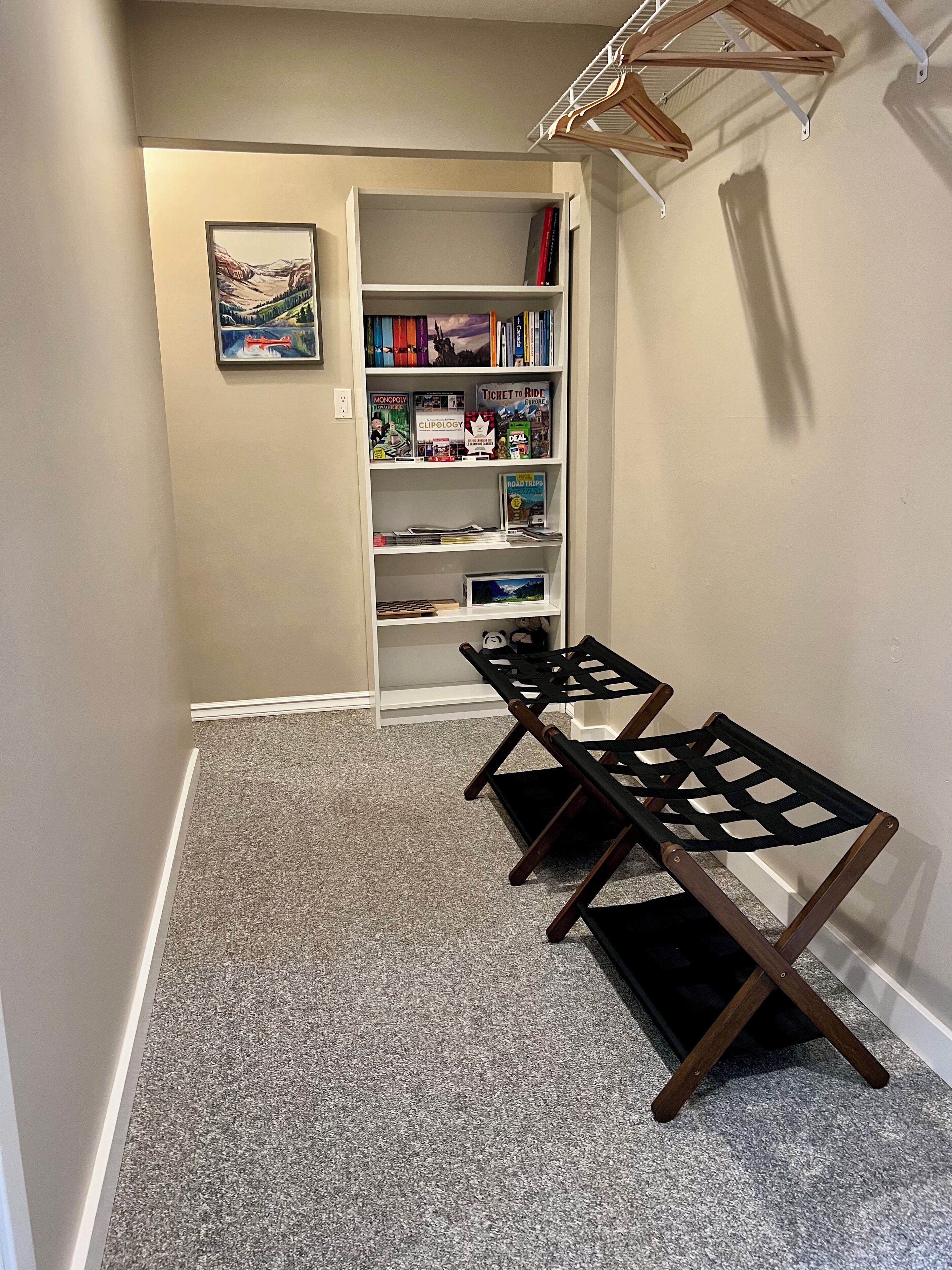 A hallway with a bookshelf, a framed picture, and two folding chairs.