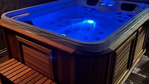 A hot tub with a wooden bench and a blue-lit interior.