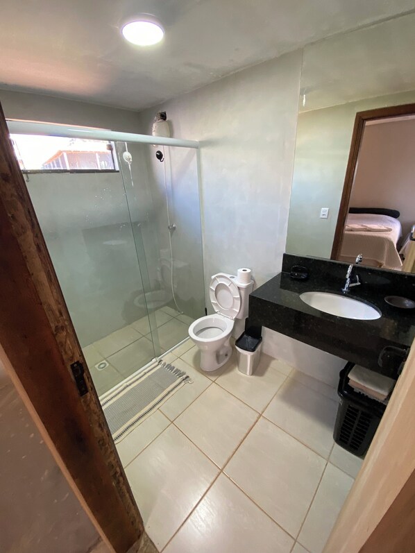 Un baño con inodoro, lavamanos y zona de ducha.