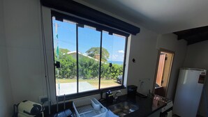 A kitchen with a large window, a sink, a stove, and a refrigerator. - Villa Querência (Avare)