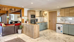 A modern kitchen with a central island, built-in appliances, and a washing machine. - Le Paradis (Orcival)