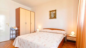 A bedroom with a bed, nightstands, a wardrobe, and a wall-mounted picture.