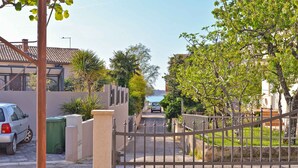 A gated residential area with a parked car and a green trash bin.