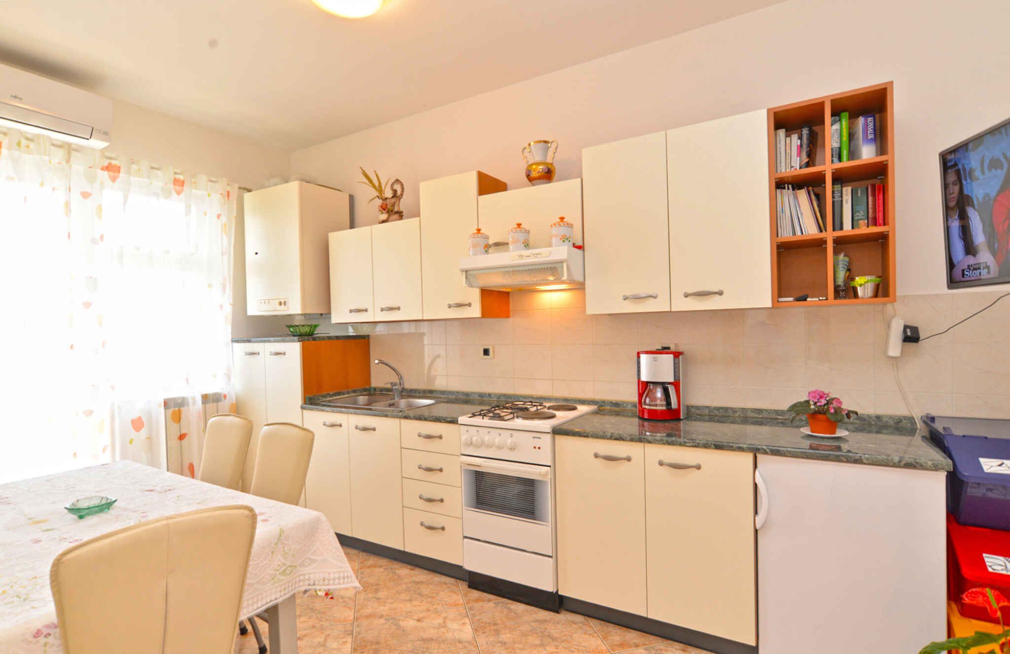A kitchen with white cabinets, a stove, a coffee maker, and a bookshelf.
