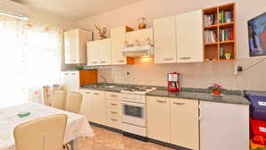 A kitchen with white cabinets, a stove, a coffee maker, and a bookshelf.