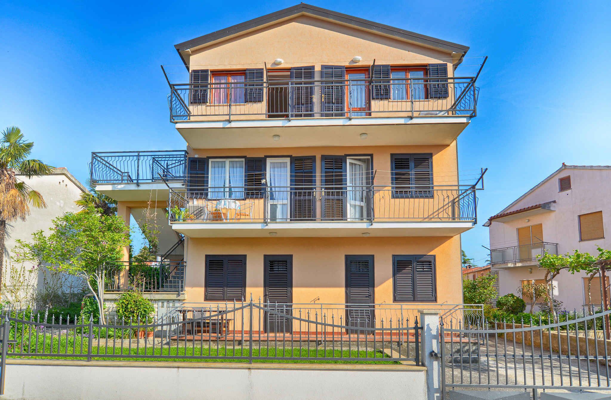 A two-story building with balconies, a gated entrance, and a small garden area.