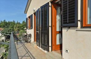A building with a balcony, outdoor furniture, and a view of trees and houses. - Holiday apartment with air conditioning (Novigrad)
