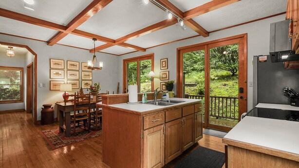 A spacious kitchen with wooden cabinets, a large island, and a view of a lush garden through sliding glass doors. - Lush, Private, & Chic Blue Ridge Retreat with 2 Fireplaces- 3 BR - 2.5 BA (Boone)