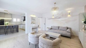 A modern living room with a sofa, two armchairs, a coffee table, and a dining area with a bar.