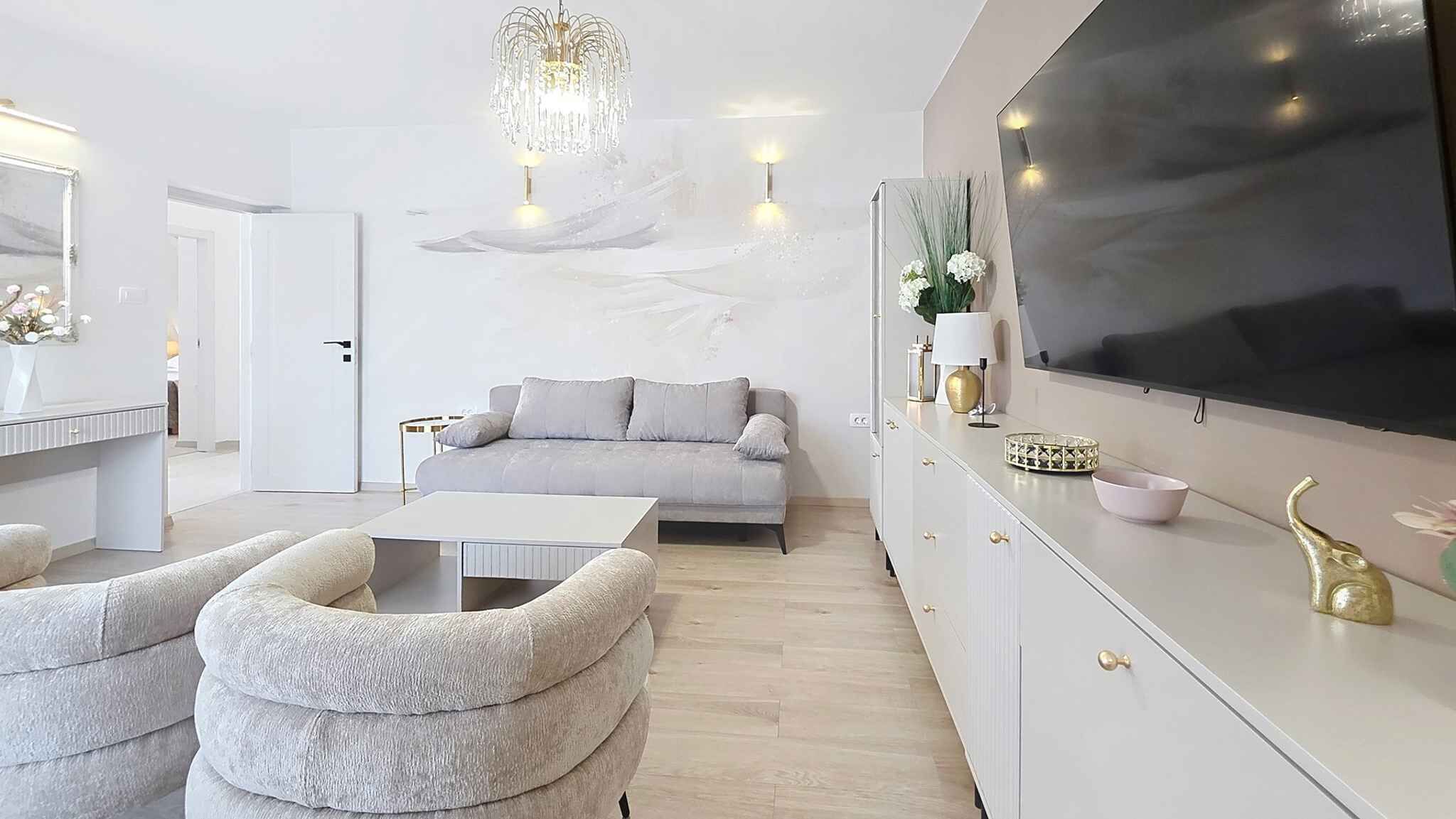 A modern living room with a sofa, a coffee table, and a TV mounted on the wall.
