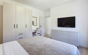 Un dormitorio con cama, cómoda, televisor y espejo.