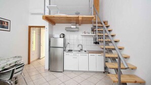 Eine kleine Küche mit Einbauherd, Spüle und einer Holztreppe.