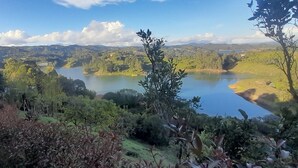 A scenic view of a lake surrounded by lush greenery and hills. - Suite Gold Rocks Glamping (El Penol)