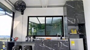 A compact kitchen with a large window, a built-in fan, and a refrigerator. - Suite Gold Rocks Glamping (El Penol)