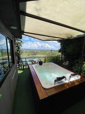 A hot tub on a balcony with a view of a lake and mountains. - Suite Gold Rocks Glamping (El Penol)
