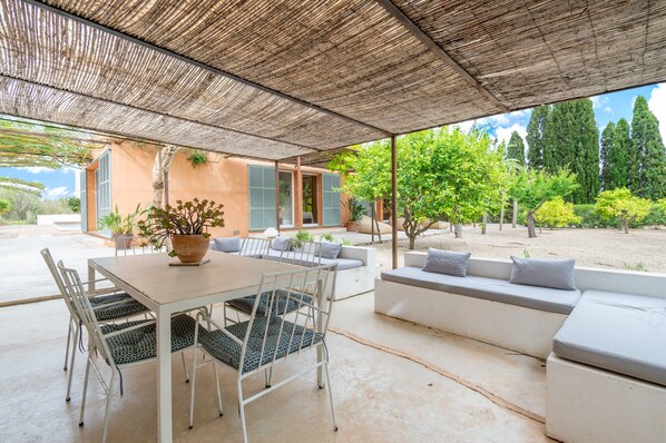An outdoor patio with a table and chairs, a sofa area, and a covered seating area.