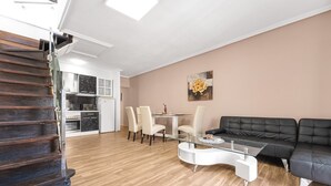 Un salon moderne avec un escalier, un coin repas et une cuisine.