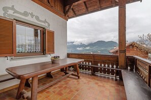 Una mesa y un banco de madera en una terraza con vistas a montañas.
