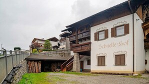 A traditional building with a wooden balcony, a stone staircase, and a sign reading 'Schneidelle-Sof.' - Apartment 'Klein' with Mountain View, Shared Garden and Wi-Fi (Velturno)