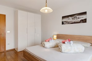 A bedroom with a bed, a wardrobe, a wall-mounted picture, and a ceiling light.