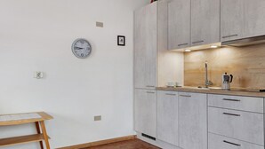 Een moderne keuken met lichtgrijze kasten, een houten aanrecht, een klok en een klein tafeltje.