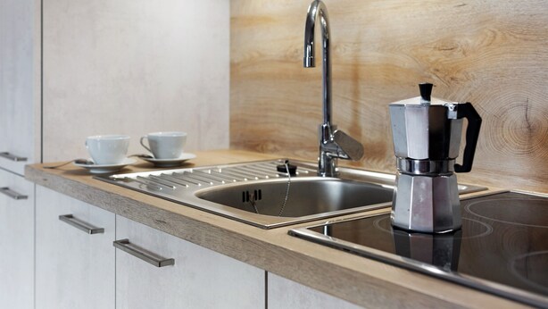 Een moderne keuken met een roestvrijstalen spoelbak, een koffiezetapparaat en een houten aanrecht.