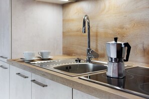 Una cocina moderna con un lavamanos de acero inoxidable, una cafetera y una encimera de madera.