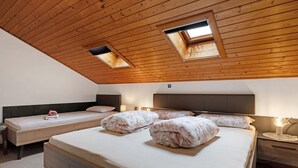 Een slaapkamer met twee bedden, dakramen, een nachtkastje met een lamp en een hoofdbord.