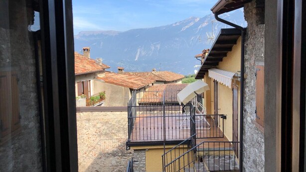 A view from a window overlooking a mountain, a courtyard with a staircase, and traditional buildings with tiled roofs. - Apartment 'Casa Mary Castagno' with Wi-Fi (Prabione)