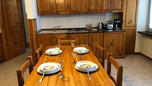 A wooden dining table set with plates, glasses, and cutlery in a kitchen with wooden cabinets and a tiled backsplash. - Apartment 'Casa Mary Castagno' with Wi-Fi (Prabione)