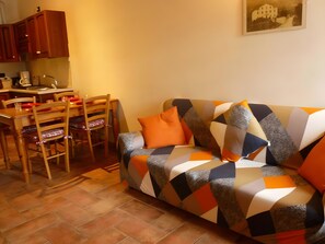 Un salon chaleureux avec un canapé à motifs, une table à manger avec des chaises et un coin cuisine.