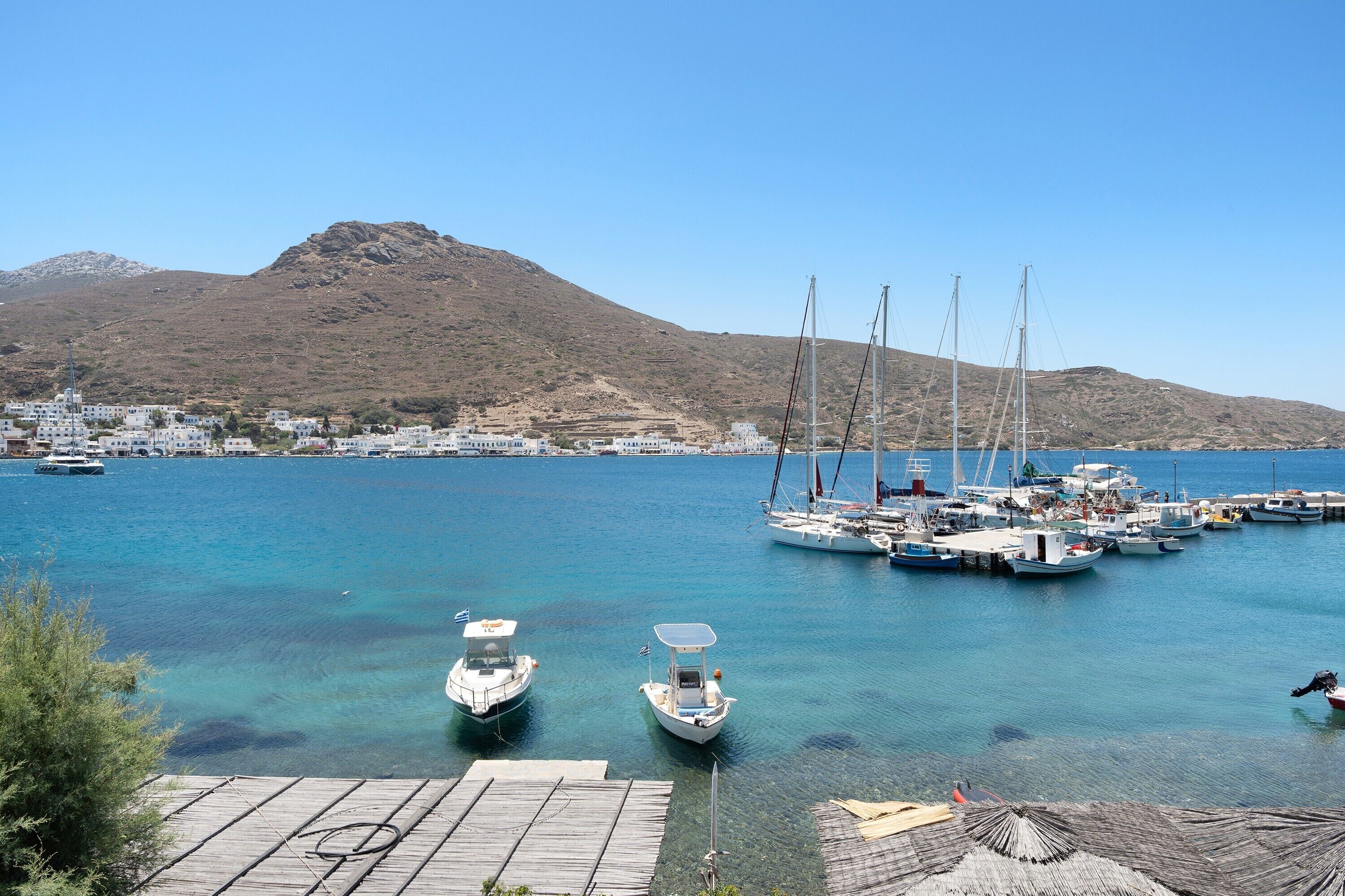 A marina with boats, a dock, and a mountainous backdrop.