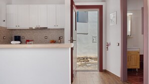 A kitchen with white cabinets, a wooden countertop, and a door leading to a bathroom. - Apartment 'Nicolas House 1' with Sea View, Wi-Fi and Air Conditioning (Rakhídhion)