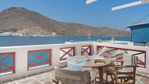 A terrace with a table, chairs, and a view of a body of water and a mountain. - Apartment 'Nicolas House 1' with Sea View, Wi-Fi and Air Conditioning (Rakhídhion)
