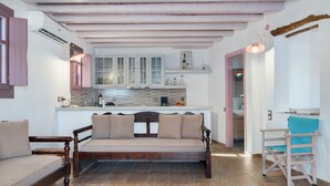 A cozy living area with a wooden sofa, a wooden chair, and a kitchen in the background. - Apartment 'Nicolas House 2' with Sea View, Private Terrace and Air Conditioning (Rakhídhion)