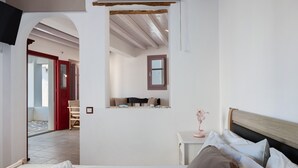 A bedroom with a bed, a bedside table, a mirror, and an arched doorway leading to another room. - Apartment 'Nicolas House 2' with Sea View, Private Terrace and Air Conditioning (Rakhídhion)