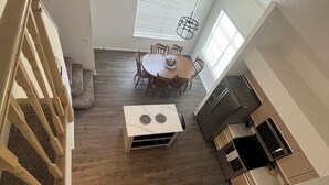 A spacious kitchen with modern appliances, a dining area with wooden chairs, and a staircase with a wooden railing.
