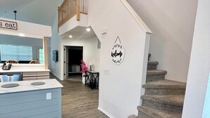 A modern interior with a kitchen area, a dining table, and a staircase leading to an upper level.
