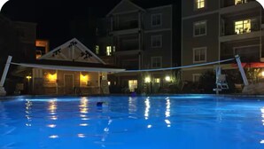 A swimming pool with a covered area and a building in the background.