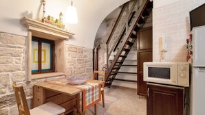 A kitchen with a wooden table, chairs, a microwave, and a staircase. - Apartment 'Home Sweet Home' with Balcony, Wi-Fi and Air Conditioning (Giovinazzo)