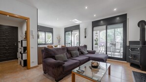 A modern living room with a sectional sofa, a glass coffee table, and a kitchen area with a stove.