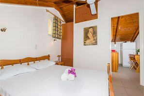 A bedroom with a wooden bed, a wooden wardrobe, a small table with a vase, and a painting on the wall. - Apartment '1' with Private Terrace, Wi-Fi and Air Conditioning (Laganas)