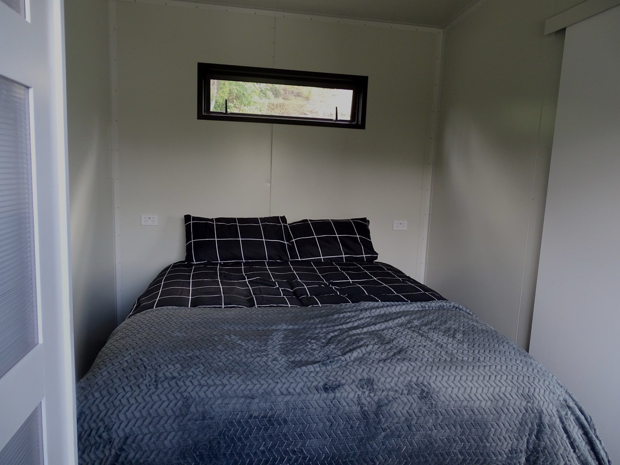 A bedroom with a bed, a window, and a door.