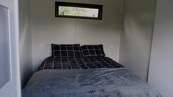 A bedroom with a bed, a window, and a door.
