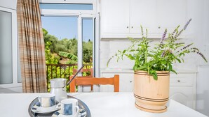 A dining table with a tray of tea set, a potted plant, and a view of a balcony with a wooden railing.