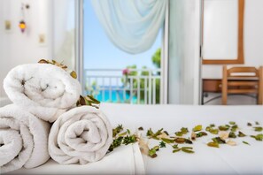 Un lit bien fait, avec des serviettes blanches pliées en rouleaux et quelques feuilles séchées éparpillées.
