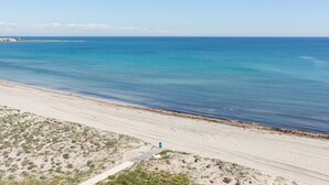 A beach with a clear view of the ocean, a sandy path, and sparse vegetation.