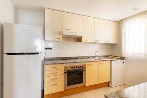 A modern kitchen with white cabinets, a stainless steel oven, a dishwasher, and a built-in stove.