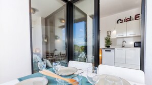 Un comedor con una mesa preparada para cuatro, un divisor de vidrio y vistas a la cocina.